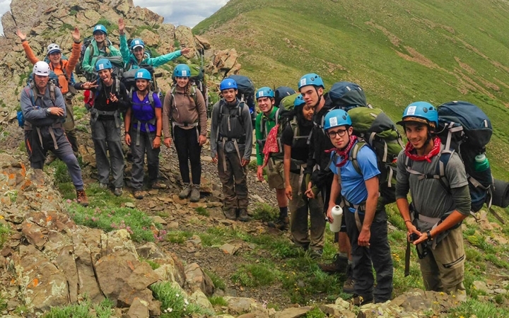 a group of backpackers stand among a grassy and rocky landscap